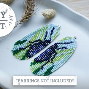May include: Two beaded earrings in shades of green, blue, and black, with a fringe design. The earrings are displayed on a white surface. The image also includes a DIY KIT logo and the text "*EARNINGS NOT INCLUDED*".