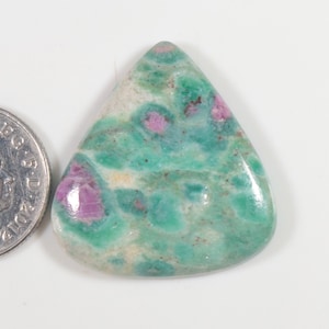 Puede incluir: Un cabujón de piedra preciosa verde, blanco y rosa con forma triangular. La piedra preciosa es aproximadamente del tamaño de una moneda de 1 euro.