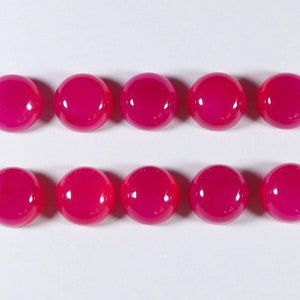 May include: Ten round, pink cabochon gemstones. The gemstones are smooth and polished.