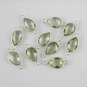 Op de afbeelding: Tien zilveren traanvormige edelsteenverbinders met twee springringen. De edelstenen zijn lichtgroen.