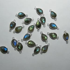 May include: A collection of 18 silver teardrop-shaped pendants with iridescent green and blue labradorite gemstones. Each pendant has two jump rings for attaching to jewelry.