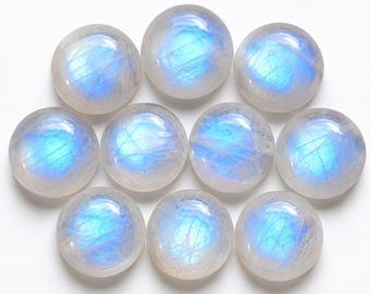 Puede incluir: Un conjunto de nueve piedras de luna redondas talladas en cabujón dispuestas en grupo. Cada gema presenta una base blanca lechosa y translúcida con una distintiva adularescencia azul brillante visible en las superficies lisas y abovedadas.