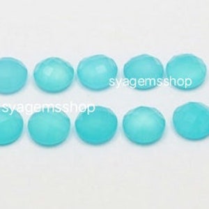 Puede incluir: Diez cabujones redondos de piedra preciosa de color azul claro, facetados. Los cabujones miden aproximadamente 10 mm de di&aacute;metro.