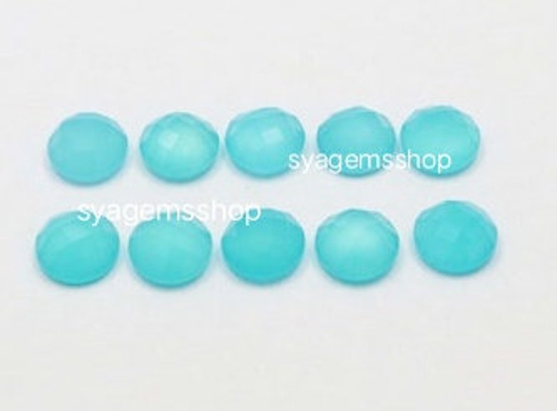 Puede incluir: Diez cabujones redondos de piedra preciosa de color azul claro, facetados. Los cabujones miden aproximadamente 10 mm de di&aacute;metro.