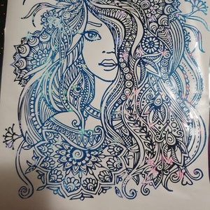 Pu&ograve; includere: Un disegno in bianco e nero di un viso di donna con intricati motivi floreali nei capelli. Il disegno ha un effetto glitter blu e rosa.