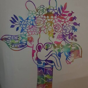 Pu&ograve; includere: Una giraffa colorata in stile acquerello con una corona di fiori. La giraffa ha un collo lungo e la lingua che sporge. I fiori sono in tonalit&agrave; di rosa, viola, blu e verde.