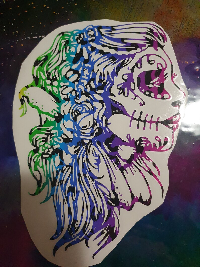 Pu&ograve; includere: Un adesivo colorato di un viso di donna con un design di teschio di zucchero. Il teschio &egrave; delineato in nero e riempito con un arcobaleno di colori. I capelli della donna sono lunghi e fluenti, e ha dei fiori nei capelli.