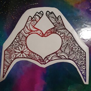 Pu&ograve; includere: Due mani che formano un cuore con intricati motivi in ​​bianco e nero su uno sfondo colorato.