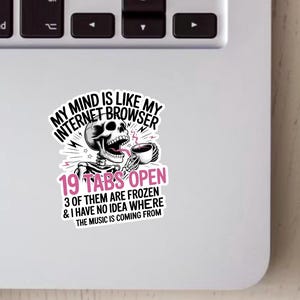Könnte beinhalten: Ein weißer Aufkleber mit einer schwarz-rosa Grafik eines Skeletts, das eine Kaffeetasse hält. Der Text lautet: "MY MIND IS LIKE MY INTERNET BROWSER 19 TABS OPEN 3 OF THEM ARE FROZEN & I HAVE NO IDEA WHERE THE MUSIC IS COMING FROM."