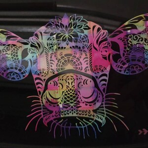 Pu&ograve; includere: Un design di testa di mucca astratto e colorato con motivi intricati e un effetto acquerello. La testa di mucca &egrave; rosa, viola, blu, verde e gialla.