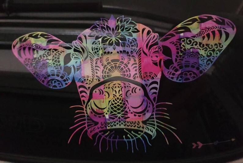Pu&ograve; includere: Un design di testa di mucca astratto e colorato con motivi intricati e un effetto acquerello. La testa di mucca &egrave; rosa, viola, blu, verde e gialla.