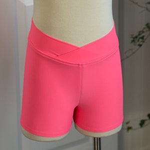May include: Hot pink athletic shorts with a criss-cross waistband.