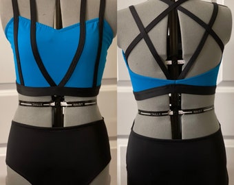 May include: A blue and black dance top with a criss-cross strap design in the back. The top is paired with black high-waisted dance shorts.