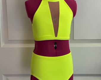 May include: A neon yellow dance costume with a halter top and high-waisted shorts. The top has a mesh panel in the front.