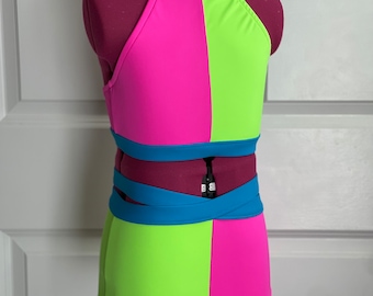 May include: A two-piece dance costume with a halter top and shorts. The top is pink and green with a blue trim. The shorts are green and pink with a blue waistband.