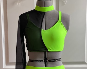 May include: A black and neon green dance costume with a long-sleeved mesh top, a cropped neon green tank top, and a black skirt with a neon green waistband. The waistband has the words "TAILLE" and "WAIST" printed on it.
