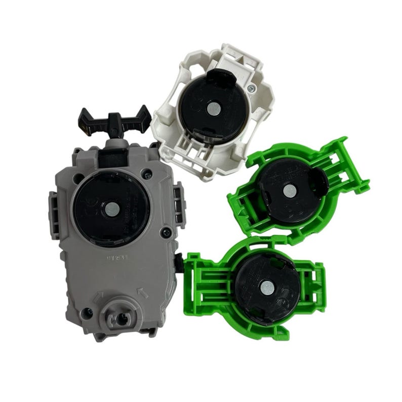 Puede incluir: Una colecci&oacute;n de lanzadores de juguetes en varios colores. El lanzador principal es gris con un mango negro, mientras que los otros son blancos y verdes. Cada lanzador tiene un componente negro circular en el centro.