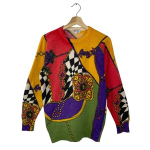 May include: A multi-coloured sweater with a geometric and floral pattern. The sweater is made of a soft, fuzzy material and has a crew neck. The sweater has a label that says "URBOXS".