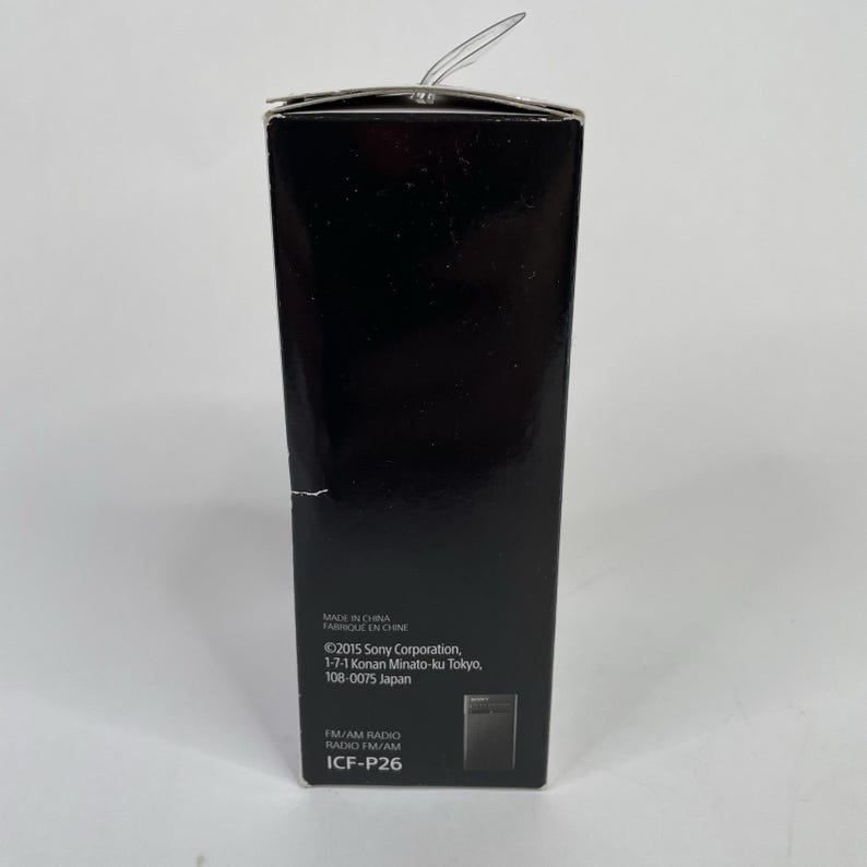 May include: A black rectangular box with the text "MADE IN CHINA" and "&copy;2015 Sony Corporation" printed on it. The box also has the text "FM/AM RADIO RADIO FM/AM ICF-P26". A clear plastic tab is visible at the top.