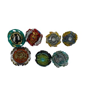 Puede incluir: Una colecci&oacute;n de siete peonzas coloridas. Las peonzas presentan varios dise&ntilde;os y combinaciones de colores, incluyendo verde, rojo, dorado y azul. Est&aacute;n dispuestas sobre un fondo blanco.