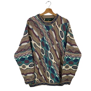 May include: A brown, green, and blue patterned sweater with a crew neck. The sweater has a geometric design and is made of a soft, knitted fabric.