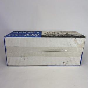 May include: A rectangular box with blue and white panels. The top panel has the brand name "brother" and the model number "TN-430" printed in blue and black. The box is sealed with clear tape and sits on a white surface.
