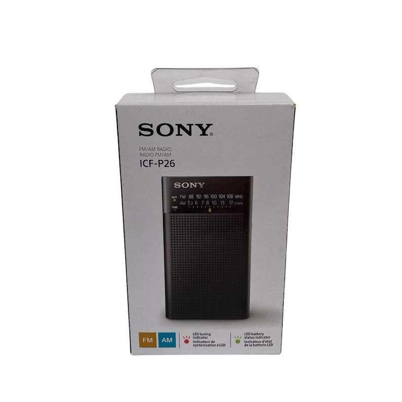 May include: A black Sony ICF-P26 FM/AM radio is shown in its packaging. The radio has a speaker grill and a tuning dial. The white box features the Sony logo and radio specifications.