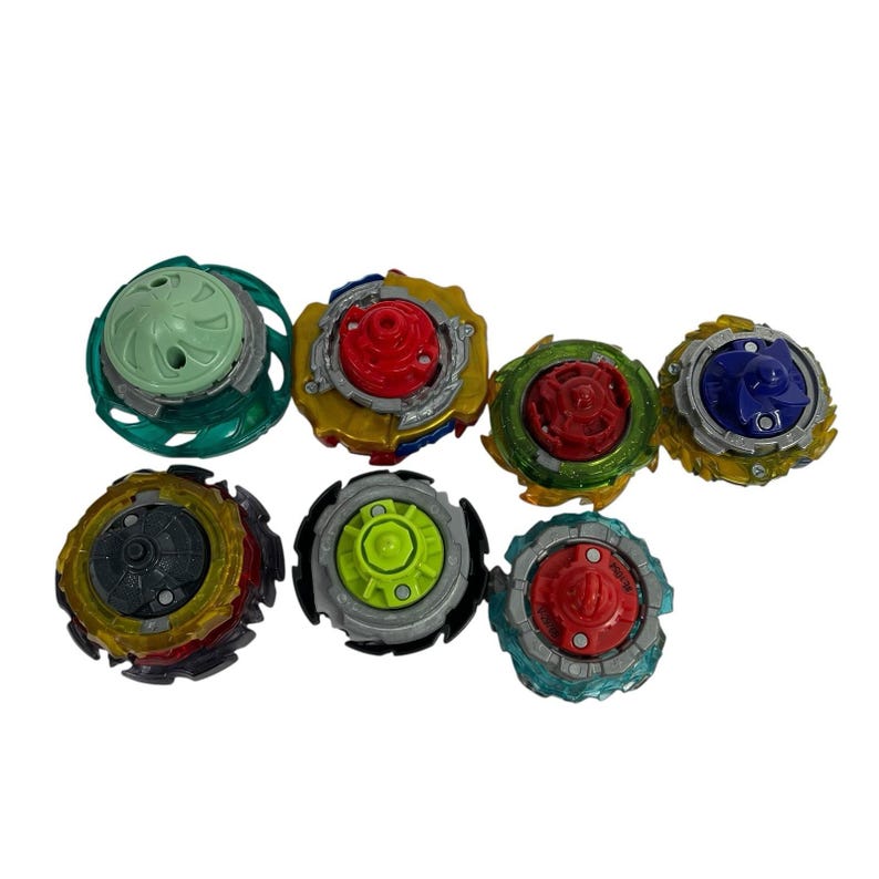 Puede incluir: Una colecci&oacute;n de siete peonzas coloridas. Cada peonza presenta un dise&ntilde;o &uacute;nico con varios colores, incluyendo rojo, verde, azul, amarillo y gris. Las peonzas est&aacute;n hechas de pl&aacute;stico y metal, y est&aacute;n dise&ntilde;adas para jugar.