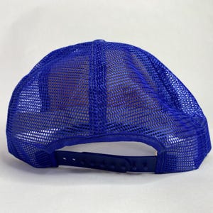 May include: A blue trucker hat with a mesh back and a curved brim. The hat features a snapback closure for adjustable sizing. The mesh is a lighter shade of blue than the front of the hat.