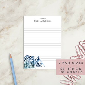 May include: A personalized notepad with a watercolor illustration of mountains and trees. The notepad has lined paper and says "A note from Nicholas Bachman" at the top. The notepad is available in 7 pad sizes: 50, 100, or 150 sheets.