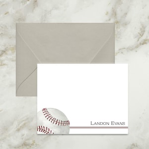 May include: A white rectangular stationery card featuring a watercolor baseball illustration in the bottom left corner, two horizontal maroon lines, and the printed name LANDON EVANS in dark gray text, accompanied by a light gray envelope.