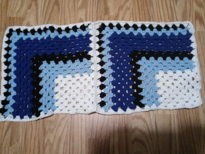 May include: A crocheted blanket with a geometric pattern in white, blue and black.