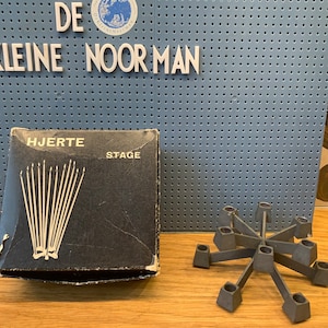May include: A black box with the text "HJERTE STAGE" on the front. The box contains a set of candles. A silver metal candelabra with eight candle holders.