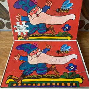 May include: A vintage 20-piece jumbo puzzle featuring a cartoon illustration of a bearded man in a blue and purple costume running away from a bee. The puzzle box is red with a yellow, green, and white border.