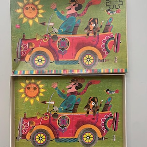 May include: A vintage jigsaw puzzle box with a colorful illustration of a red car with a man, a dog, and a bird on a green background. The box has the text "Jumbo Puzzle 500 Pieces" on the side.