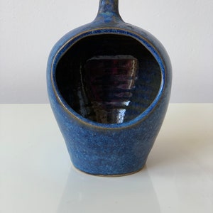 Könnte beinhalten: Eine blaue Salzschale aus Keramik mit einer runden Öffnung und einem Henkel. Die Schale hat eine gesprenkelte Glasur.