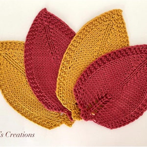 May include: Four knitted leaf-shaped items in shades of gold and burgundy. The leaves are arranged in a fan shape, showcasing their textured, hand-crafted appearance. The text "Inesa's Creations" is visible at the bottom.
