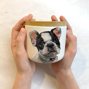 May include: White ceramic jar with a bamboo lid, featuring a hand-painted portrait of a French bulldog with black and white fur, wearing a green collar.