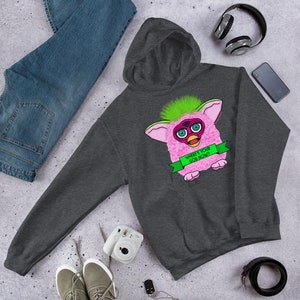 May include: A dark gray hooded sweatshirt with a pink and green Furby toy graphic. The Furby is holding a green banner that says "Where's your god now?"