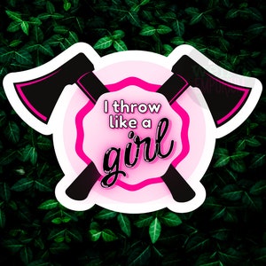 May include: A pink and white sticker with two crossed black axes. The sticker has the text "I throw like a girl" in pink.