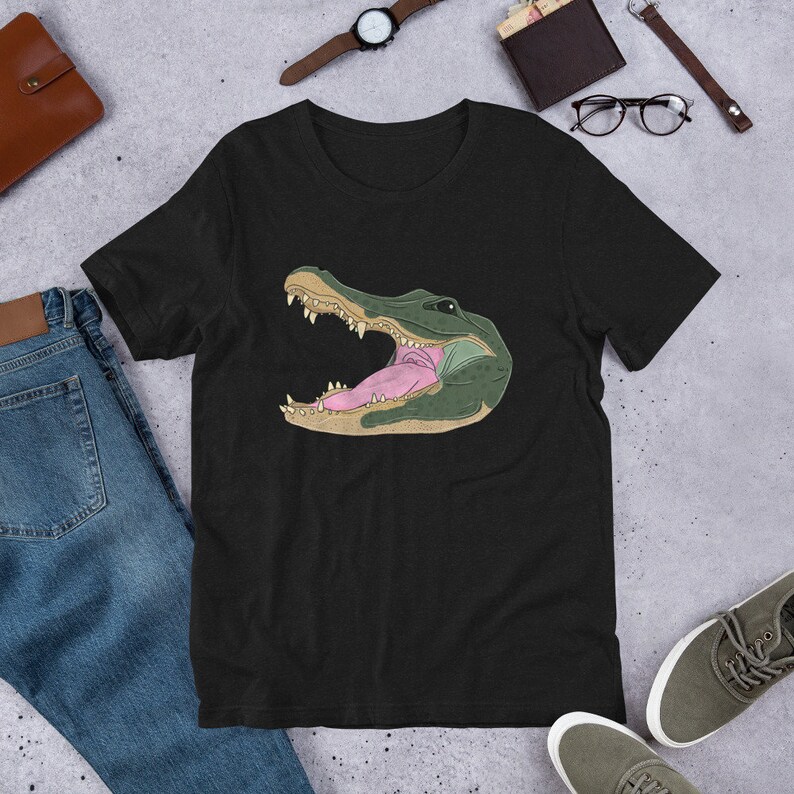 May include: Black t-shirt with a graphic of an alligator's head with its mouth open and tongue sticking out.