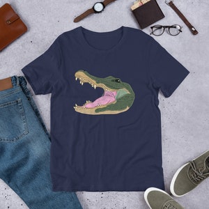 May include: A navy blue t-shirt with a graphic of an alligator's head with its mouth open, showing its teeth and tongue.