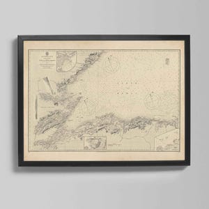 May include: A framed vintage nautical chart of Scotland, featuring detailed coastlines, depth soundings, and navigational markers. The map is printed on aged paper and encased in a black frame, suitable for home decor.