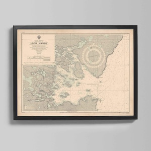 May include: Framed vintage nautical chart of Loch Maddy, with detailed coastlines, depths, and navigational markers. The chart features a compass rose and text that reads "Loch Maddy". The frame is black.