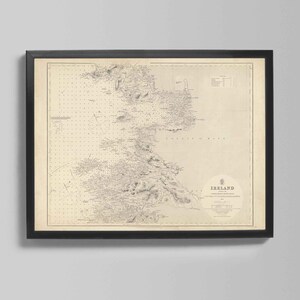 Könnte beinhalten: Gerahmte Vintage-Karte von Irland in einem schwarzen Rahmen. Die Karte ist in Sepia-Tönen gehalten und zeigt detaillierte Küstenlinien, geografische Merkmale und Text. Das Wort "Irland" ist unten in der Mitte der Karte zu sehen.