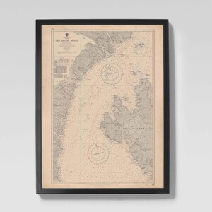 May include: Framed vintage nautical chart titled "The Little Minch" with a black frame. The chart features detailed coastlines, compass roses, and depth soundings in a beige and gray color scheme. A decorative piece for maritime enthusiasts.