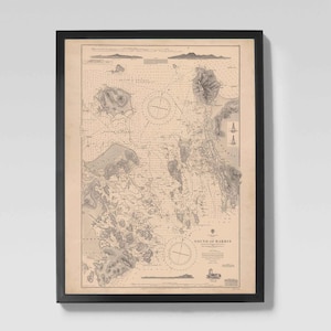 May include: Framed vintage nautical chart of the Sound of Harris, featuring detailed coastlines, islands, and navigational markers. The map is in shades of beige and gray, with a black frame. The title "Sound of Harris" is visible.