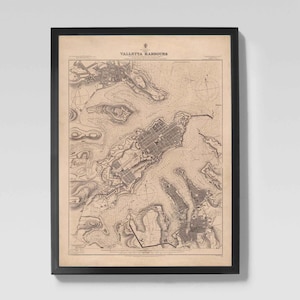 May include: Framed vintage map print of Valletta Harbours. The map is in sepia tones with black text and details, set within a black frame. The map shows the city's layout and surrounding areas.