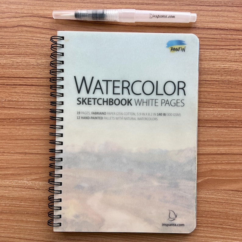 May include: A spiral-bound watercolor sketchbook with white pages, featuring a landscape cover image, the text WATERCOLOR SKETCHBOOK WHITE PAGES, 19 pages, 5.9 in x 8.2 in, 140 lb, and a clear water brush pen with the text insparea.com printed on it.