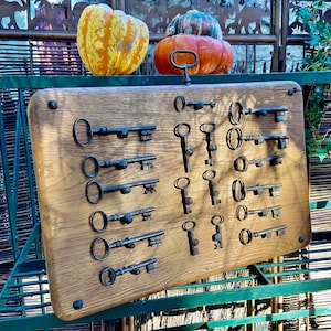 May include: A wooden board with a collection of antique keys displayed on it. The keys are various sizes and shapes, and some have decorative details. The board is mounted on a green metal frame.